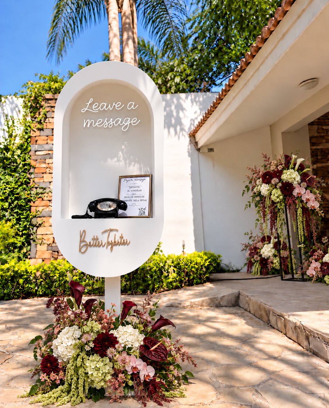 La Vida's arched audio guestbook stand with a vintage telephone and burgundy florals